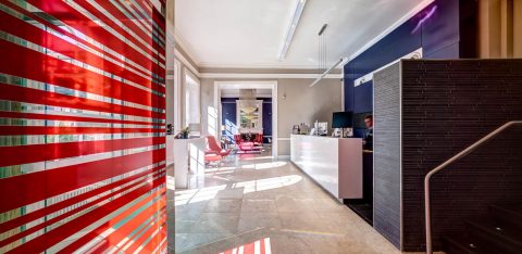 Reception area of a hotel, with smart white fittings and red furniture